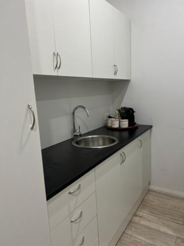 a kitchen with a sink and white cabinets at Spirit of Bondi Apartments in Sydney