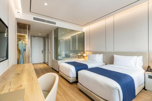 a hotel room with two beds and a table at Arbour Hotel and Residence in Pattaya Central
