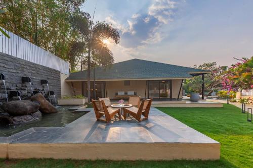 a patio with a table and chairs in a yard at StayVista's Lush Villa - Rustic-Meets-Modern Interiors, Pool, Jacuzzi & Indoor activities in Wādhiware