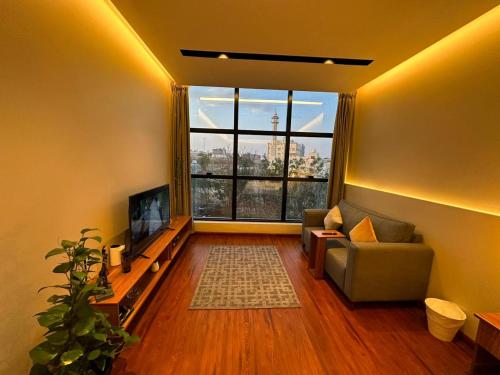 sala de estar con sofá y ventana grande en مساكن خاصة بتصميم فندقي ووصول ذاتي, en Taif