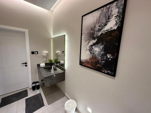 a bathroom with a sink and a large painting on the wall at مساكن خاصة بتصميم فندقي ووصول ذاتي in Taif
