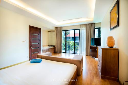 um quarto de hotel com uma cama e uma televisão em Villa Tourane em Da Nang