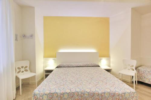 1 dormitorio con 1 cama y 2 sillas blancas en Villa Cristina, en Lignano Sabbiadoro