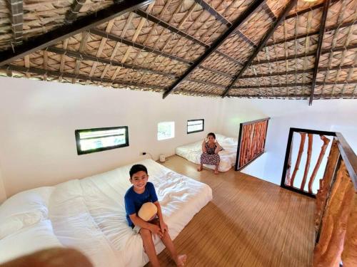 Ein kleiner Junge auf einem Bett in einem Zimmer in der Unterkunft Cozy Cabin Casita Anahaw in Indang