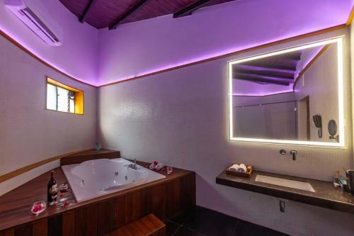 een badkamer met een bad en een grote spiegel bij StayVista's Lush Villa - Lake-View Haven with Rustic-Meets-Modern Interiors, Pool, Jacuzzi & Indoor activities in Wādhiware