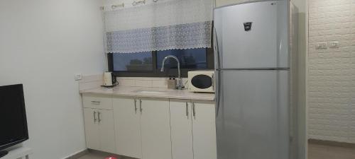 a white kitchen with a refrigerator and a sink at פינה קטנה בערבה in Beʼer Ora