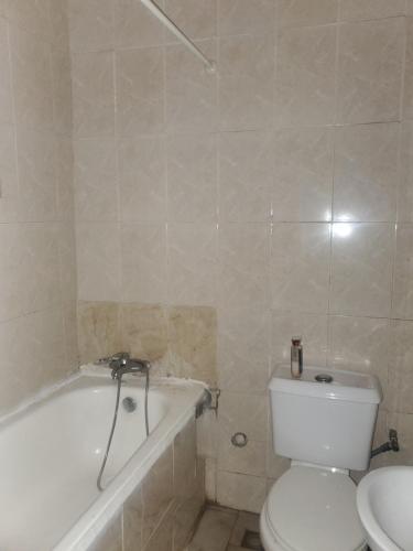 uma casa de banho com um WC, uma banheira e um lavatório. em Miraph Apartment em Abuja