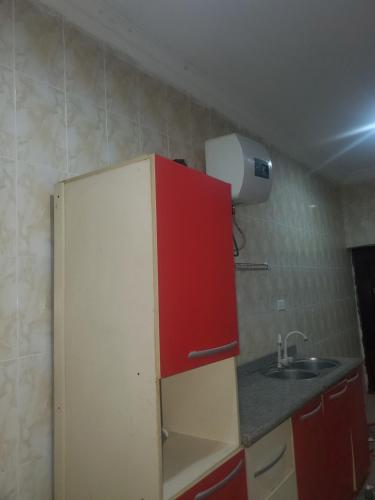 uma cozinha com um armário vermelho e um lavatório em Miraph Apartment em Abuja