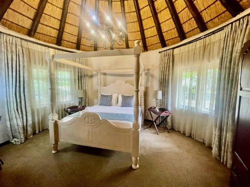 um quarto com uma cama branca num quarto com janelas em Black Eagle Hotel & Spa em Roodepoort