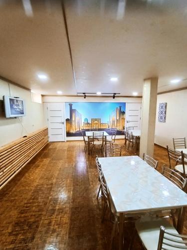 een kamer met tafels en stoelen en een muurschildering aan de muur bij Hotel Suzani Samarkand in Samarkand