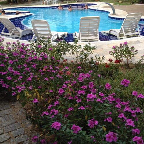 two chairs and flowers next to a swimming pool at Recanto da Praia in Paraty
