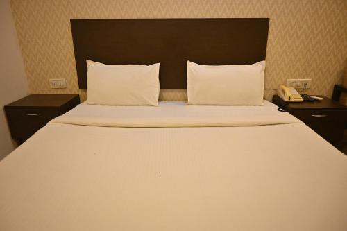 a bedroom with a large white bed with two pillows at Regency Square Hotel in Gwalior