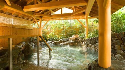 a swimming pool with a stream in a wooden structure at Shimobe Hotel in Minobu