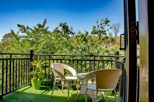 two chairs and a table on a balcony at Prakriti Aalay - Riverside Mountain View Boutique Eco Resort in Dharamshala