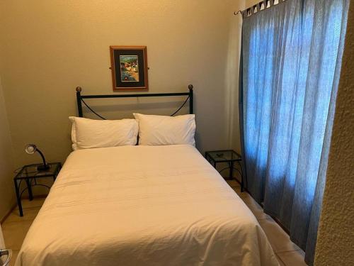 a bed with white sheets and a blue curtain at 86 Pendleberry Holiday Grove in Warmbaths