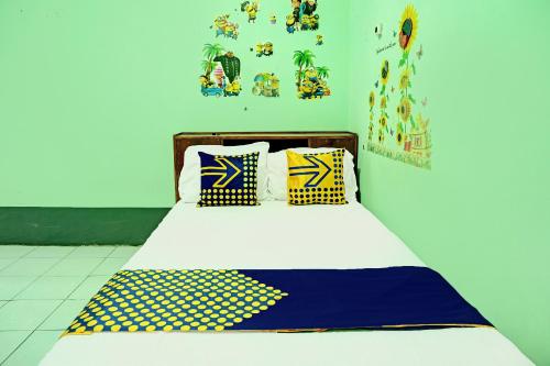 Bett mit gelben und blauen Kissen in einem Zimmer in der Unterkunft SPOT ON 92400 Dhaha Penginapan House Syariah in Kediri