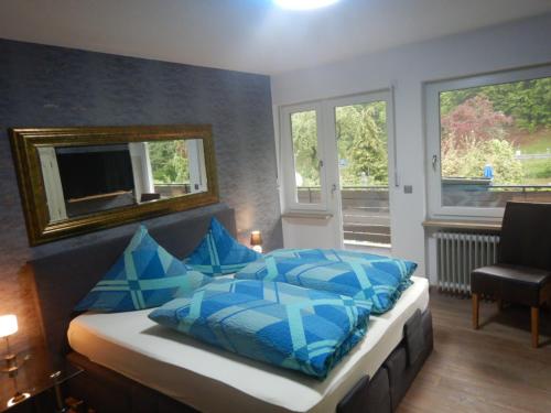 ein Schlafzimmer mit einem Bett mit blauen Kissen und einem Spiegel in der Unterkunft Pension Pulvermühle in Waischenfeld