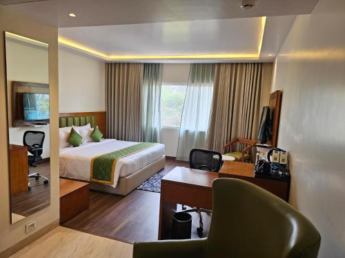 a hotel room with a bed and a desk and a mirror at Quality Inn Rockwell Grand, Bangalore in Bengaluru