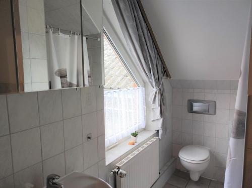 a bathroom with a toilet and a sink and a window at Ferienwohnung "Günni" in Nübbel