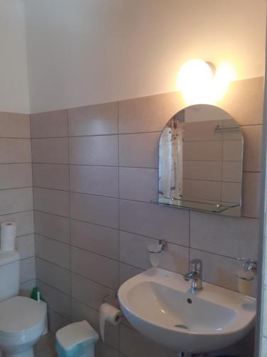 a bathroom with a sink and a mirror and a toilet at Porto Heli Apartments in Palekastron