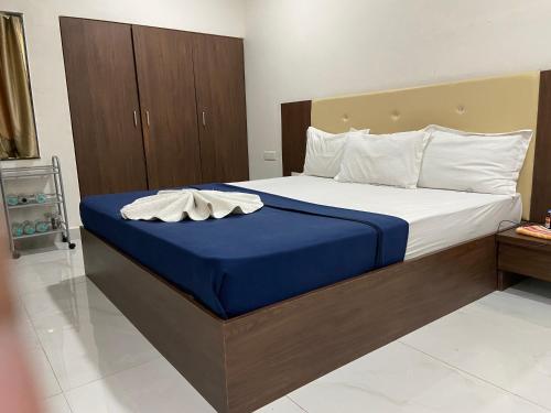 1 dormitorio con 1 cama grande con manta azul en Hotel Millennium Plaza, en Jamnagar