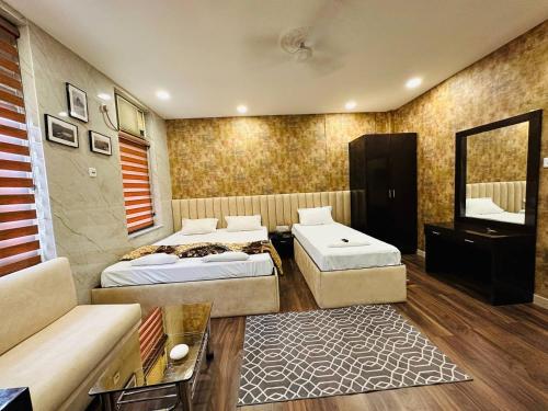 a room with two beds and a couch and a television at Hotel Majestic in Kolkata