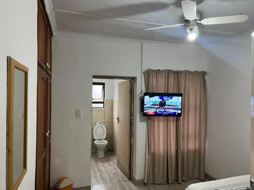 a room with a tv on a wall with a toilet at Empangeni guest house in Empangeni