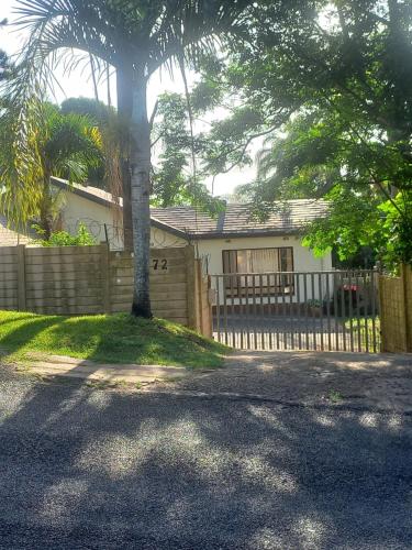 a house with a fence and a palm tree at Empangeni guest house in Empangeni