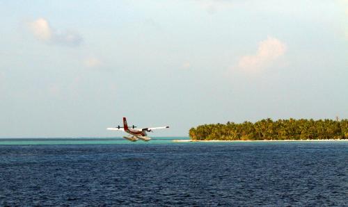 a plane flying over an island in the ocean at Brickwood Rasdhoo- Beach front in Rasdu
