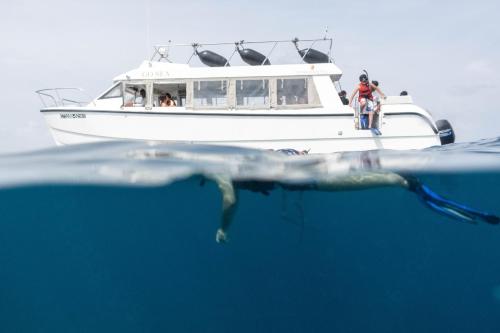 a person on a bike in front of a boat in the water at Brickwood Rasdhoo- Beach front in Rasdu