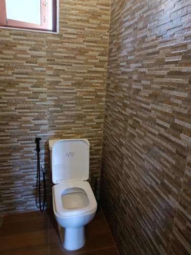 La salle de bains est pourvue de toilettes blanches et d'un mur en briques. dans l'établissement Apartmán Sudu Nangy, à Beruwala