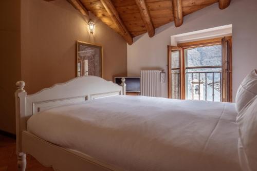 1 dormitorio con cama blanca y ventana en Appartamento Filomena by LakeSweetLakeComo, en Laglio