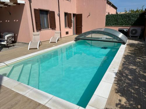 a swimming pool with a glass door and a house at Villa con piscina riscaldata ad uso esclusivo, aperta tutto l'anno in Lascari