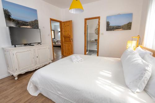 1 dormitorio con 1 cama blanca y TV de pantalla plana en שופרא ריזורט - וילה ובקתות - נופש וספורט Shoofra Resort Vacation Nature and Sport, en Manot