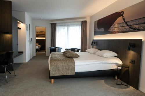 Cette chambre comprend un lit et une grande fenêtre. dans l'établissement Hotel Apostroff, à Coxyde