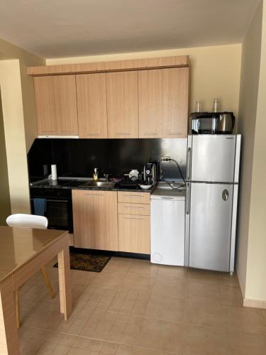 a kitchen with a stainless steel refrigerator and wooden cabinets at Green Life apartment Sozopol in Sozopol