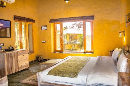 a bedroom with a large bed and a window at Prakriti Aalay - Riverside Mountain View Boutique Eco Resort in Dharamshala