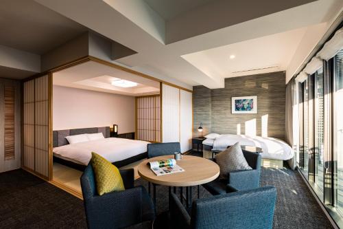 京都Rinn Kyoto Station的酒店客房带两张床和一张桌子以及椅子。