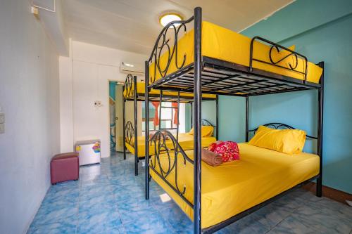 two bunk beds in a room with yellow beds at Noble Thippanate in Chiang Mai