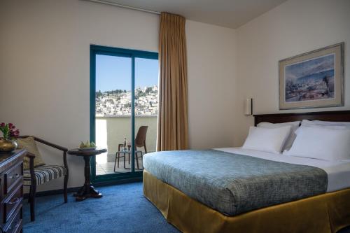 ein Hotelzimmer mit einem Bett und einem großen Fenster in der Unterkunft Mary’s Well Nazareth By Dan Hotels in Nazareth
