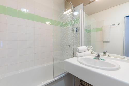 ein weißes Bad mit einem Waschbecken und einer Dusche in der Unterkunft Appart'City Classic Lyon Part Dieu Villette in Lyon