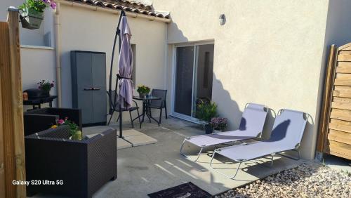 a patio with two chairs and an umbrella at MAS GABELYS superbe vue SAINTE VICTOIRE jardin terrasse et piscine in Trets