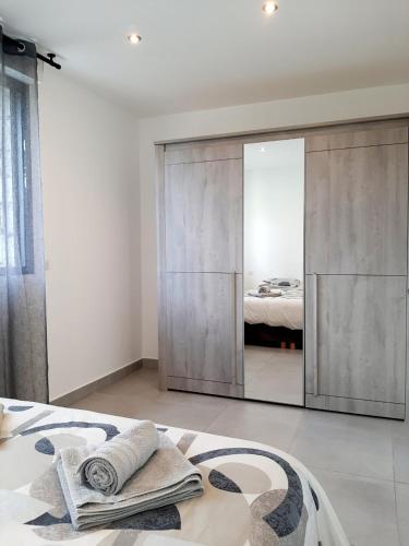 - une chambre avec un grand placard miroir et un lit dans l'établissement N5 Maison T2 climatisé, à Ajaccio