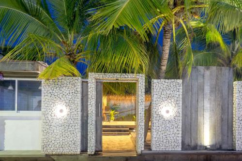 a room with two palm trees in front of a building at Brickwood Rasdhoo- Beach front in Rasdu