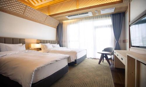 a hotel room with two beds and a television at Jeonju Tourist Hotel kkotsim in Jeonju