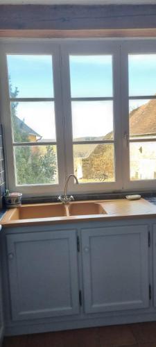 - une cuisine avec deux fenêtres et un évier dans l'établissement Gîte familial au calme au coeur du Périgord Vert, à Jumilhac-le-Grand