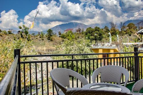 two chairs and a table on a balcony with mountains at Prakriti Aalay - Riverside Mountain View Boutique Eco Resort in Dharamshala