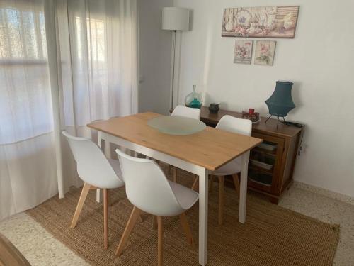 - une table en bois avec des chaises blanches dans l'établissement Apartamento Los Pinares, à Chipiona