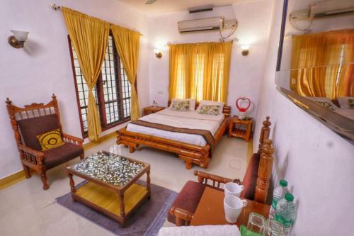 een slaapkamer met een bed, een stoel en een tafel bij Peter's Inn in Cochin
