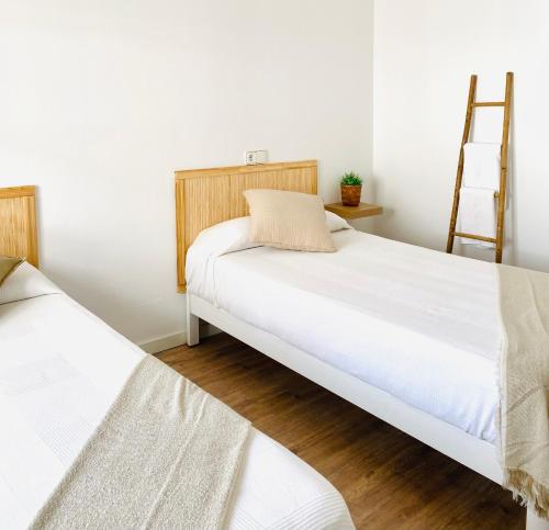 two beds in a room with white walls and wooden floors at La Bartola Guesthouse in Ibiza Town